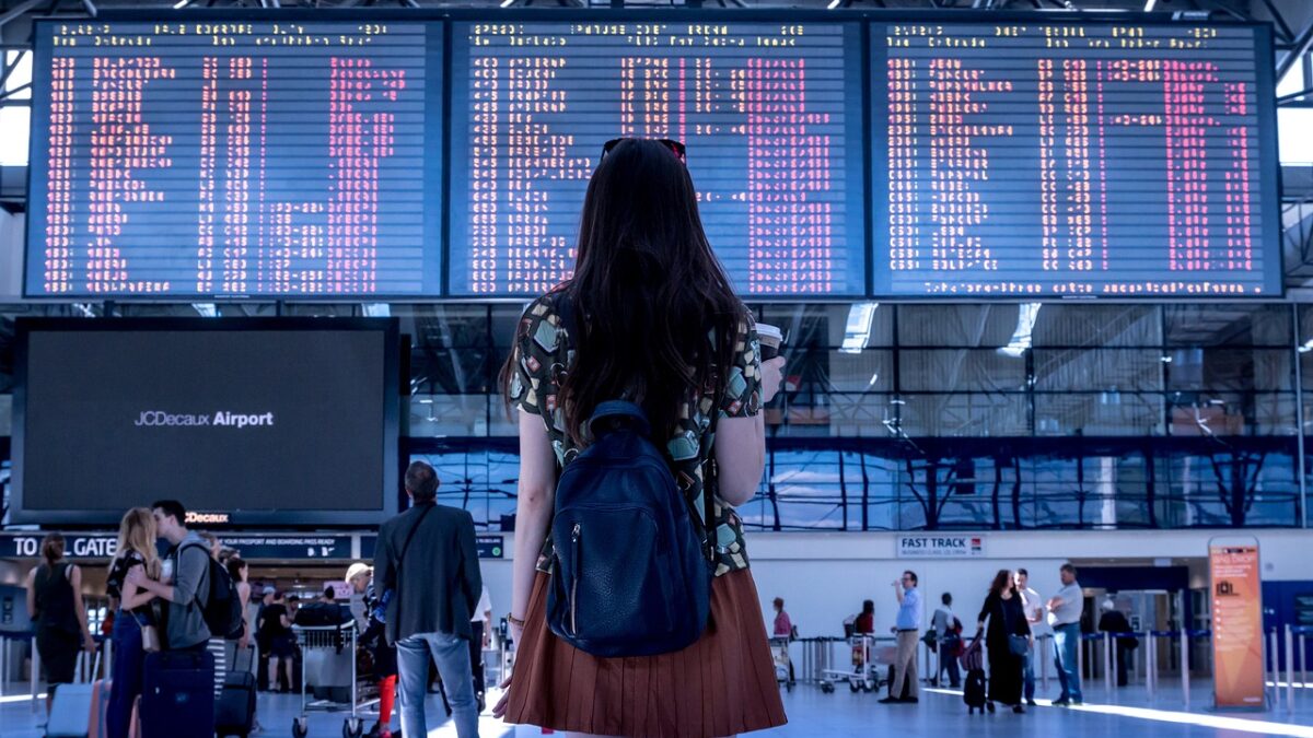 Young lady standing looking at airport schedule signs