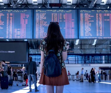 Young lady standing looking at airport schedule signs