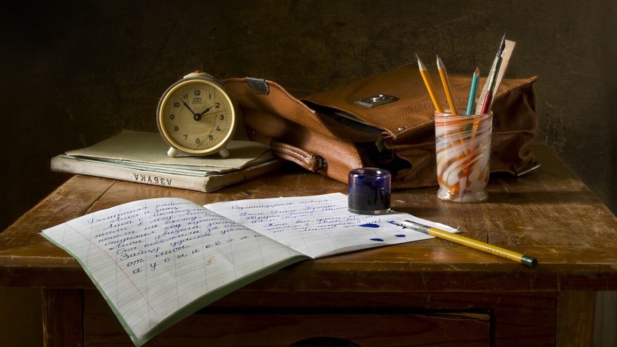 Workbook with pencils and a clock